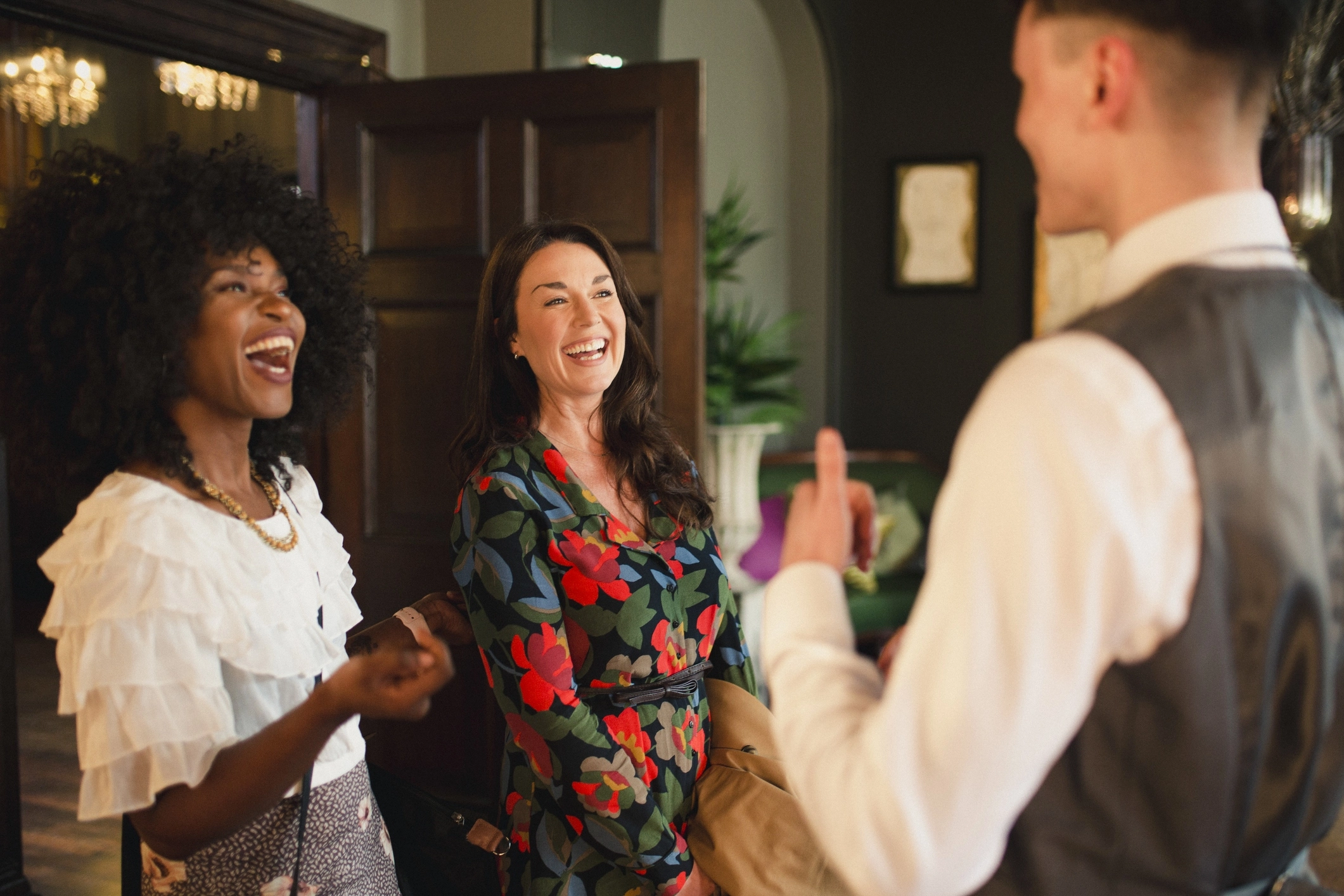 A side view shot of a hotel guests talking with the hotel concierge in the lobby.