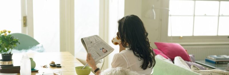 woman drinking coffee reading newspaper
