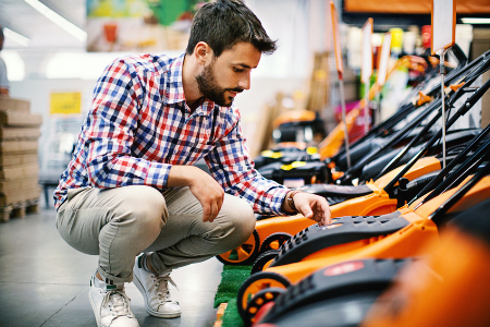 Man shopping at a hardware or home improvement store might be experiencing decision fatigue while picking out a lawn mower