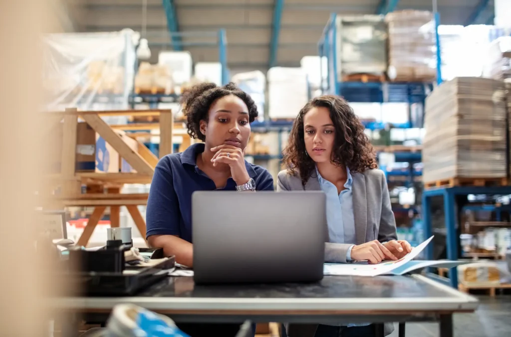 Two people looking at a computer screen in a warehouse