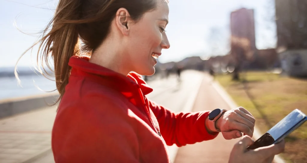 Brand Partnership blog image showing a runner looking at her smart watch and phone at same time