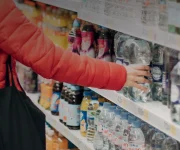 Person at store grabbing bottle water off store shelf